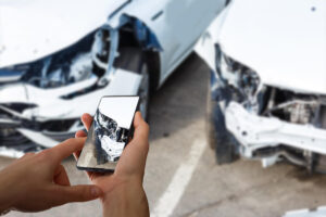 visão de uma pessoa segurando tirando foto de dois carros batidos