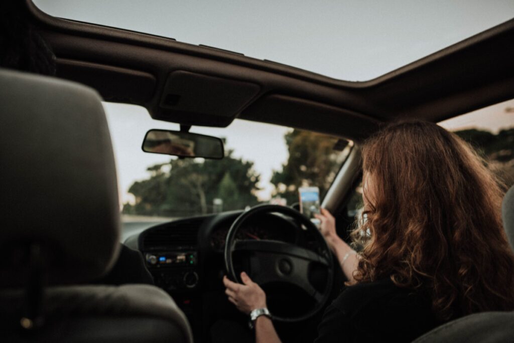 Mulher dirige veículo enquanto procura rota em aplicativo de navegação
