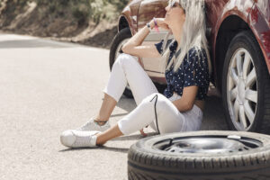 sad-young-woman-sitting-near-broken-down-car-road