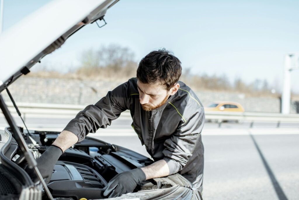 Auto mechanic repairing car outdoors