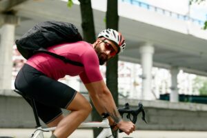Ciclista com capacete e óculos de segurança olha por cima do ombro antes de fazer uma conversão